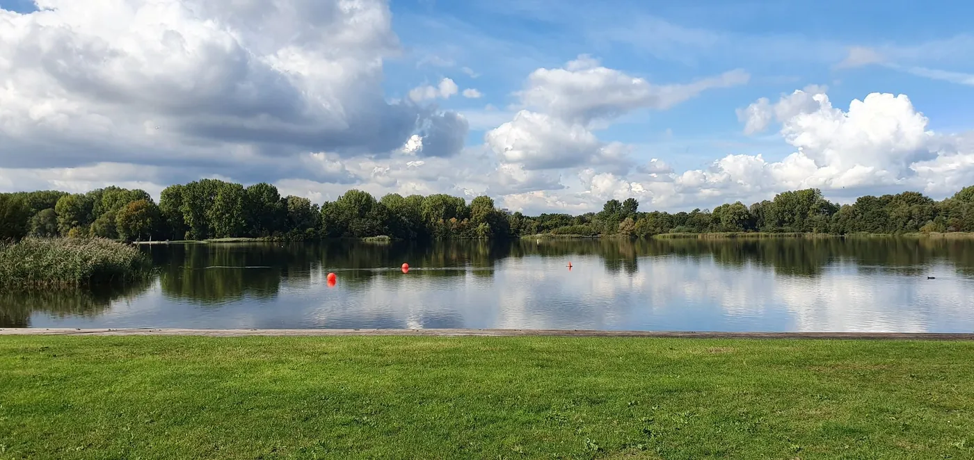 Gaasperplas, water en bomen onder een wolkenlucht