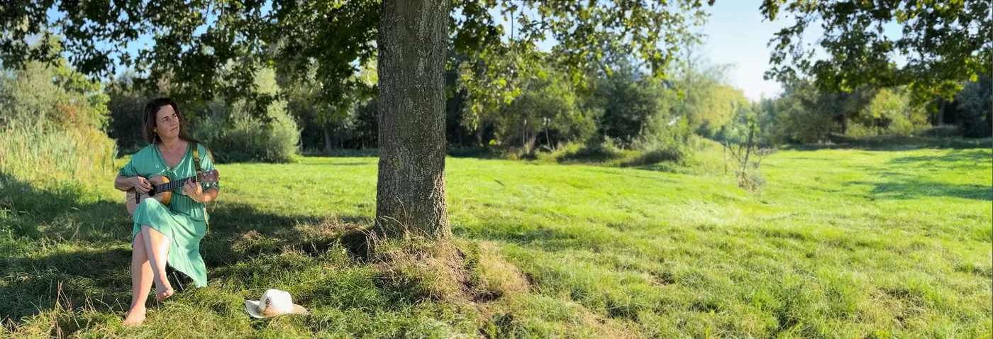 Karin met ukelele onder een boom in het gras