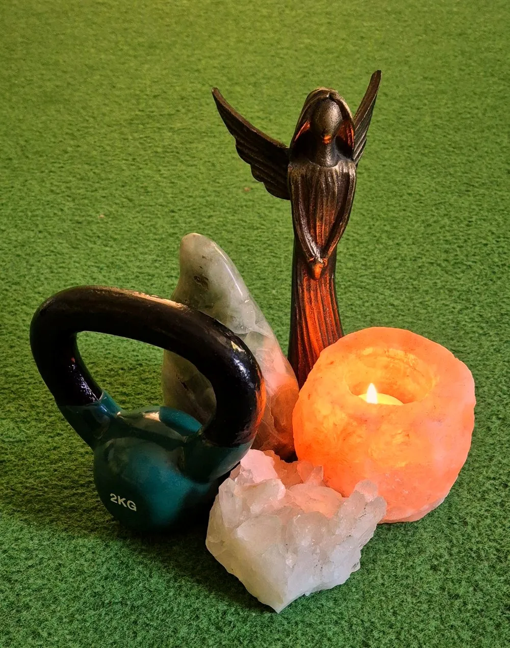 Kettlebell, kristallen, een bronzen engel en een zoutlamp met kaarslicht